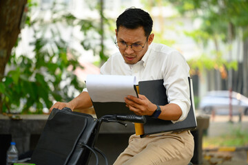 Serious busy businessman sitting on his bicycle and checking business documents