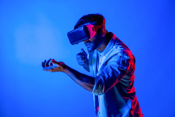Side view of man wearing VR glass and moving gesture holding gun. Gamer using future digital...