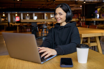 Young businesswoman watching video on laptop while sitting in cafe