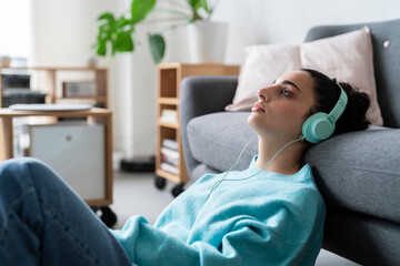 A young woman enjoys music through her headphones while lounging on the floor with vinyl records