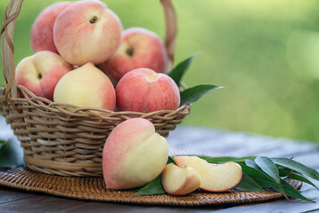 Fresh Peach with sliced on the wooden table over blurred greenery background, Fresh peach on wooden basket in wooden Background.