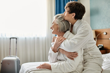 Elderly lesbian couple share a tender hug in a hotel room.