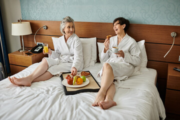 Seniors embracing each other on bed in hotel room.