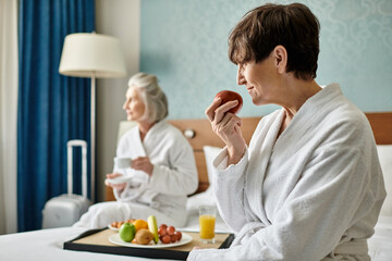 A warm senior lesbian couple comfortably seated on top of a plush bed.