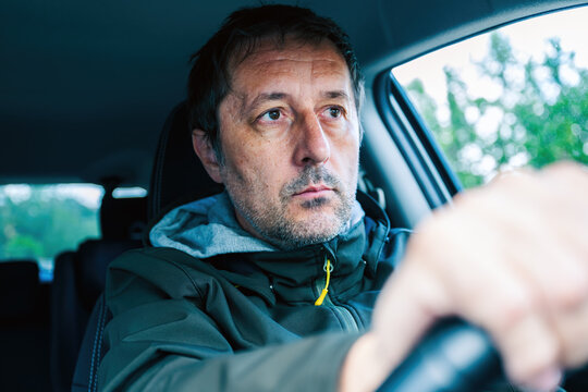 Closeup portrait of cautious male driver gripping the steering wheel and driving a car on a road trip