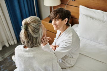 Senior lesbian couple sharing a tender moment on a bed.