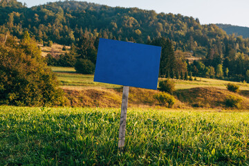 Blue information wooden sign board mockup in scenic alpine meadow in morning