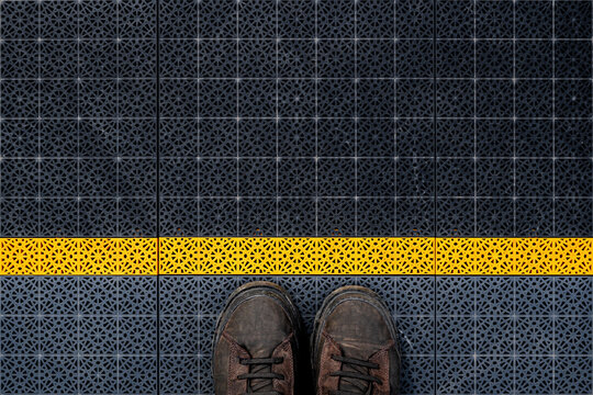Waiting line, male boots on non slip plastic flooring with triangular pattern from above