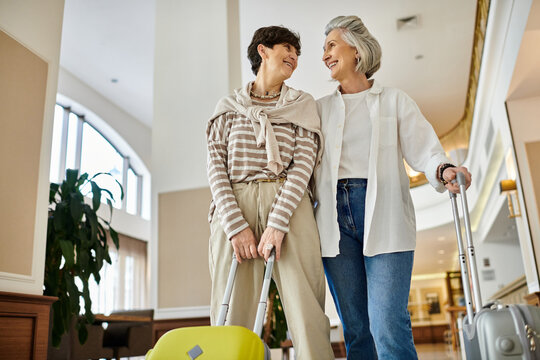 Senior lesbian couple carrying luggage, ready for a new adventure.