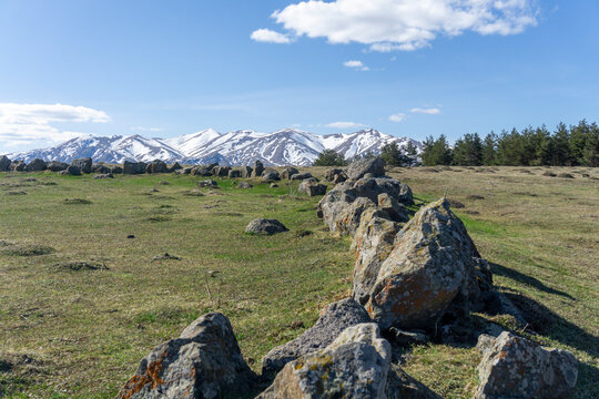 Prehistoric settlement and snow covered mountains near Tejisi willage. Green grass, bright blue sky and clouds