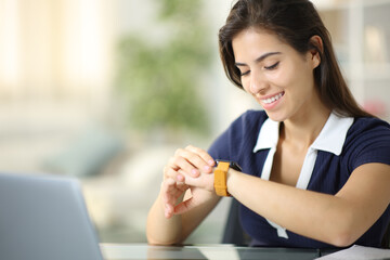 Happy woman checking smartwatch content at home
