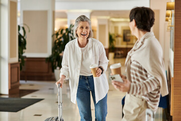 Senior lesbian couple walks with her luggage.