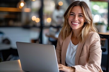 Happy business woman sitting at a desk using a laptop