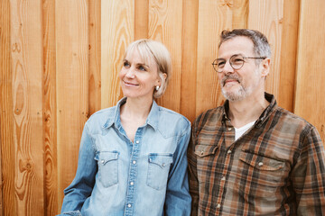 Happy Middle-Aged Couple Smiling Outdoors in Front of a Wooden Wall