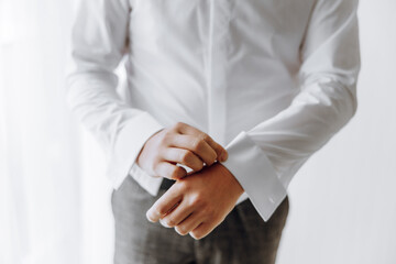 A man in a white shirt is adjusting his shirt sleeves. Concept of formality and attention to...