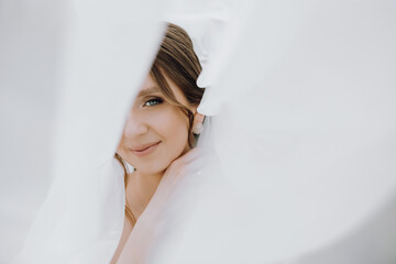 A bride is smiling and looking at the camera while her veil is pulled back to reveal her face