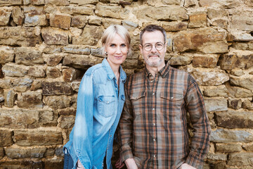 Happy Middle-Aged Couple Smiling Outdoors in Front of Stone Wall