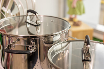 Two stainless steel pots of different size on the shelf in the kitchen or in the store, close up,...