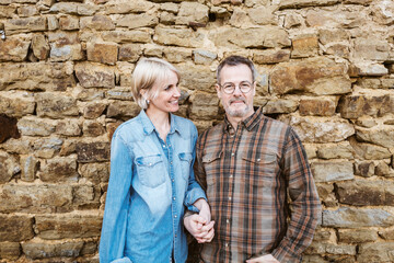 Happy Middle-Aged Couple Embracing Outdoors Against a Stone Wall