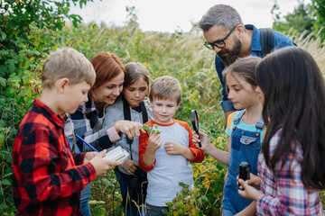 Young students learning about nature, forest ecosystem during biology field teaching class,...