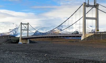 Fototapeta na wymiar A bridge over a snowy mountain with a car driving across it