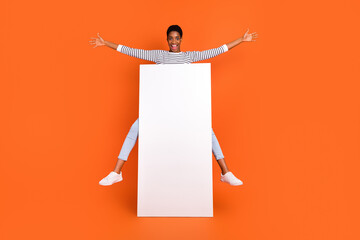Photo of excited funky third gender person wear pullover jumping modern device empty space isolated orange color background