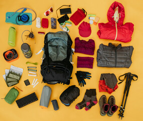 Hiking travel kit arranged on yellow background