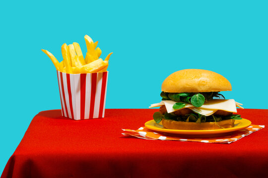 Cheeseburger with french fries on table against blue background