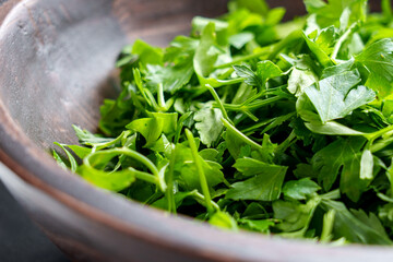 Fresh chopped green parsley leaves in wooden rustic bowl. Aromatic herbal seasoning. Petroselinum...