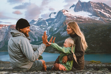 Family having fun outdoor traveling together in Norway mountains: mother, father and child on summer vacations hiking adventure trip healthy lifestyle parents playing with kid