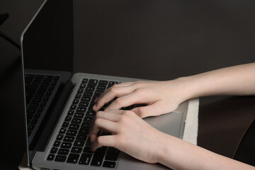 Close-up shot of a teenager's hands hovering over a laptop keyboard, showcasing computer literacy and modern technology skills.