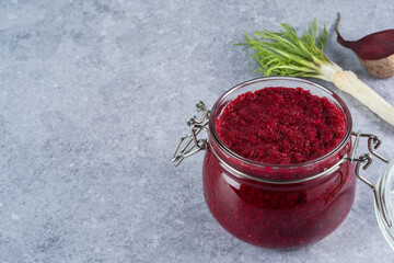 Beet horseradish sauce in jar on a gray background. Appetizer or condiment for meat and fish. Healthy vegan food. space for text