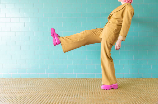 Woman standing on one leg near turquoise tile wall