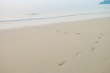 Footprints of human feet on the sand near the water on the beach.