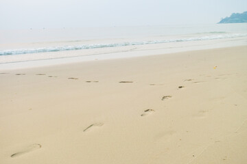 Footprints of human feet on the sand near the water on the beach.