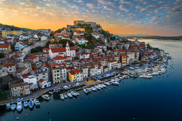 Sibenik, Croatia - Aerial panoramic view of the mediterranean old town of Sibenik on a sunny summer morning with Saint James Cathedral, Fortress of Saint Michael and dramatic golden sunrise  - Powered by Adobe