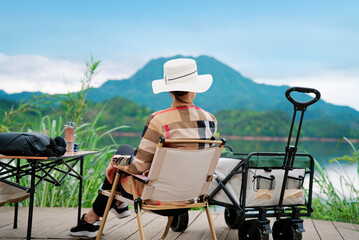 A woman is sitting on a chair and enjoying the beautiful lake and mountain scenery.