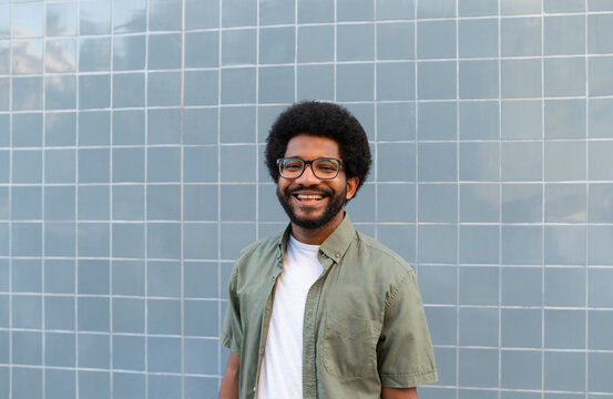 Smiling young man standing in front of tiled wall