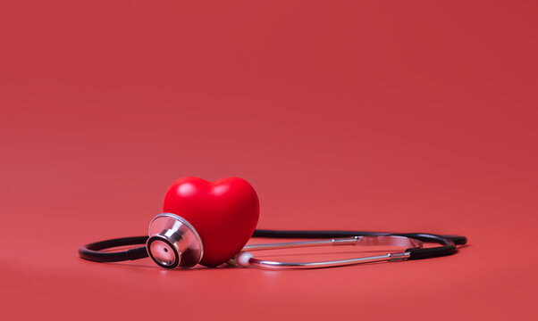 Red heart shape  exercise ball with doctor physician's stethoscope on red background, hospital life insurance concept, world heart health day. doctor day, world hypertension day,