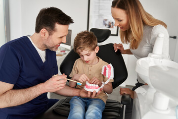 Dentist showing child how to brush teeth