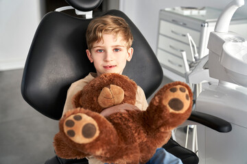 Child holding a teddy bear at the dentist's office