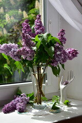 a bouquet of lilacs in a glass vase on the windowsill on a sunny day