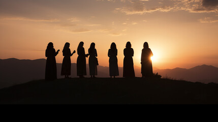 A group of Christian believers gathers at sunrise and sunset, silhouetted against the sky, coming...