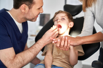 Mother supporting son having visit at dentist