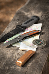 Knife, map, harmonica and compass wooden table in the forest, the concept of traveling and relaxing...