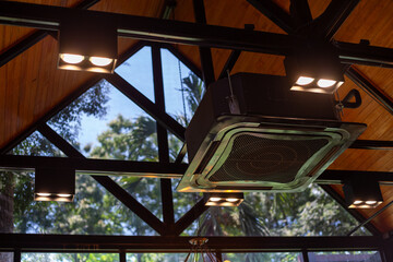 Modern black ceiling-mounted square air conditioner. In a modern cafe, There is space for text.