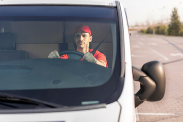 Young courier man driving car, delivering parcels to customers, front view. Delivery and shipping...
