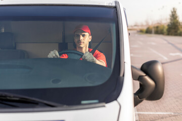 Young courier man driving car, delivering parcels to customers, front view. Delivery and shipping concept - Powered by Adobe