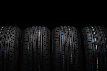 Car tires stacked in a row isolated on black background, closeup.