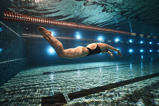 girl swimmer swims in the pool in a dark swimsuit and swimming goggles at a competition. underwater view. underwater advertising photography for swimming lessons